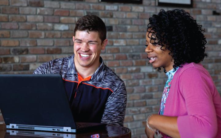 Man and woman smiling in front of computer screen
