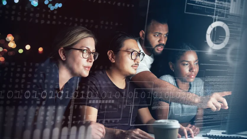 A group of four people focused on a computer screen, surrounded by digital binary code and data graphics