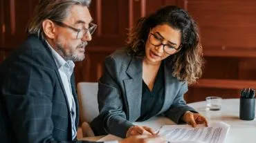 Man and women sitting at a desk reviewing paperwork.