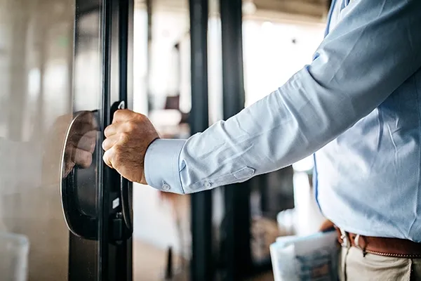 A man in a blue shirt pushes open the door of an office