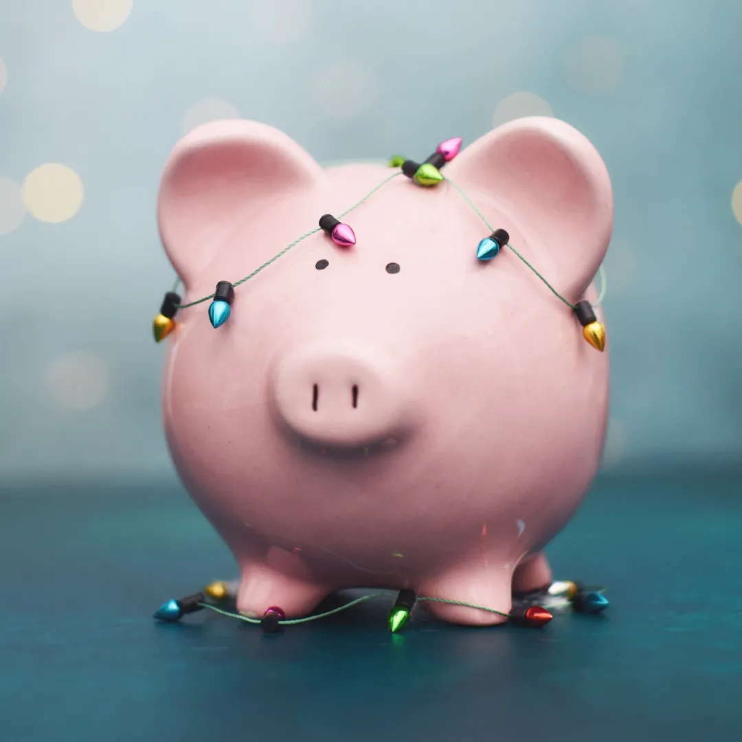 A piggy bank wrapped in holiday lights. 