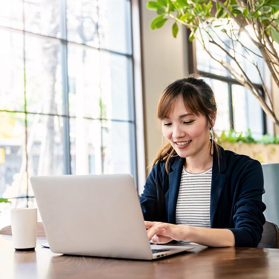 A young professional smiles while working on her laptop.