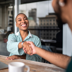 Woman smiling shaking a man's hand.