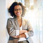 Professional woman smiling leaning against a wall.