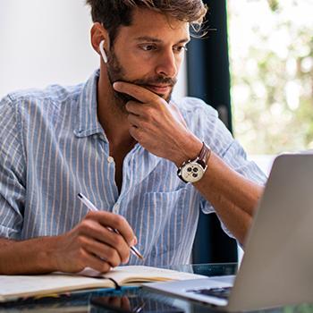 Man sitting in front of a desk looking at a laptop.