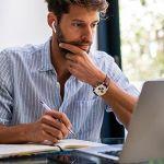 Man sitting in front of a desk looking at a laptop.
