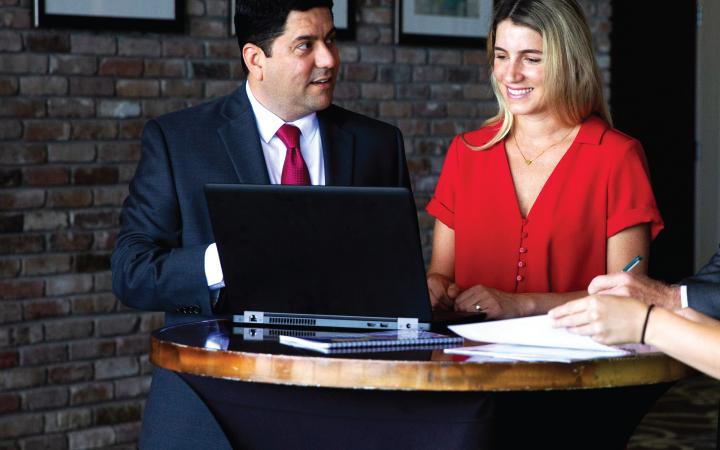 Two professionals collaborating around a computer.