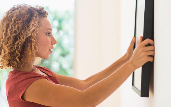 Woman hanging frame on wall