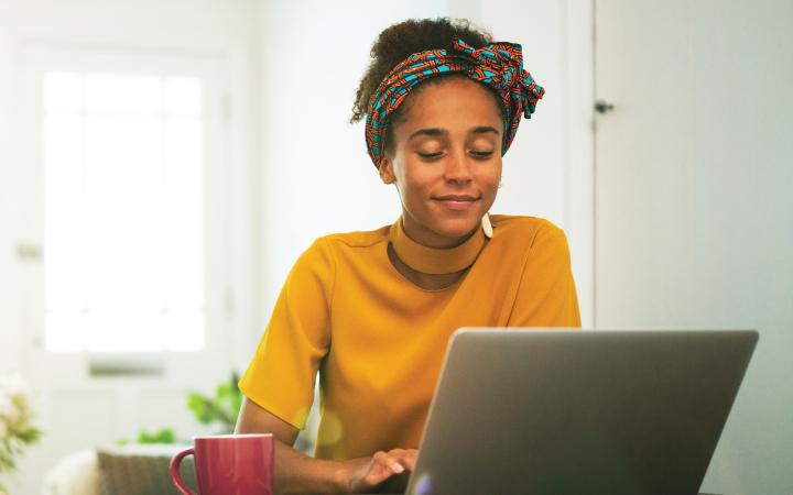 Young woman in yellow sitting in front of laptop