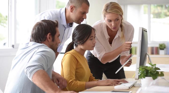 Group of people pointing at computer screen