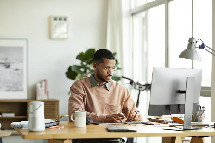 Young man on a desktop computer in a sunny bright room