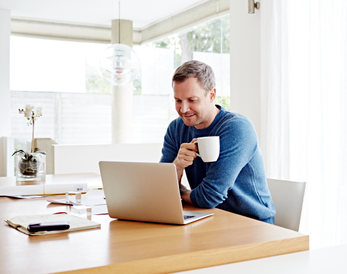 Man drinking coffee at laptop