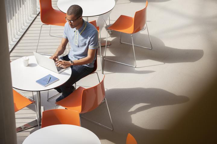 A man studying on a laptop at an outdoor cafe