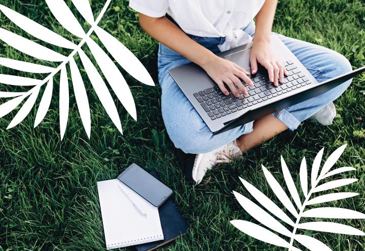 Person sitting in grass typing with palm design on image