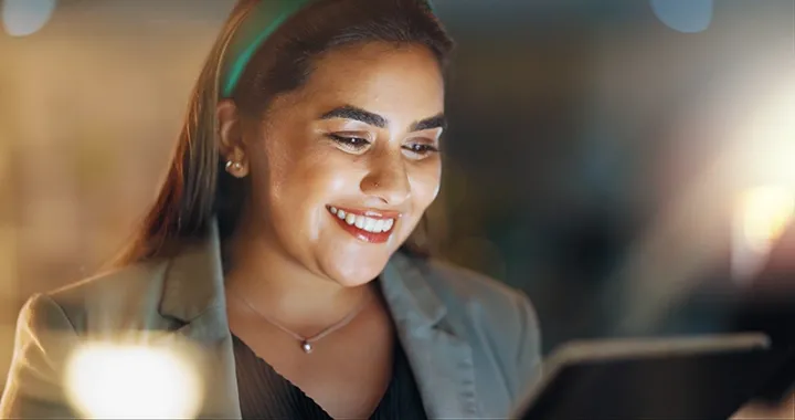 A young business woman smiles while learning on an iPad. 