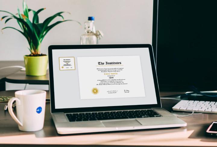 Laptop on a desk with a coffee mug next to it and a plant.