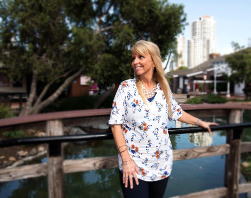 woman standing on bridge with hand on railing smiling over shoulder