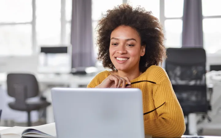 Woman in yellow sweater sitting in front of computer