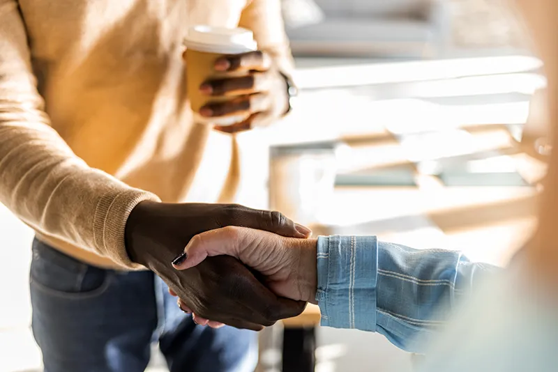 Closeup of a handshake between a young black man and a white woman wearing black nail polish