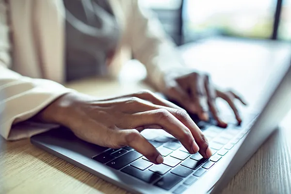 A closeup of hands on a laptop keyboard typing