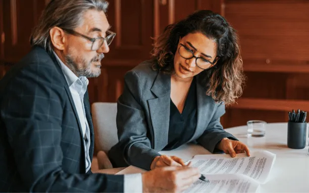Man and women sitting at a desk reviewing paperwork.